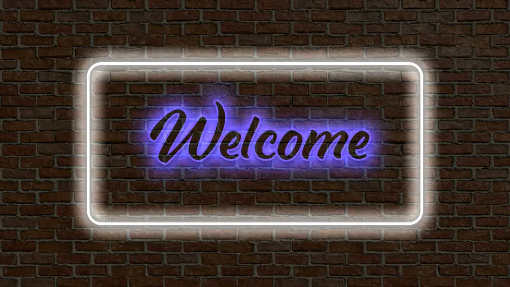 Dieses Bild zeigt einen Neonröhren-Schriftzug mit dem Wort «Welcome», der in Blau gehalten und von einem weiss leuchtenden Rahmen umgeben ist. Der Schriftzug prangt auf einer Backsteinmauer.
