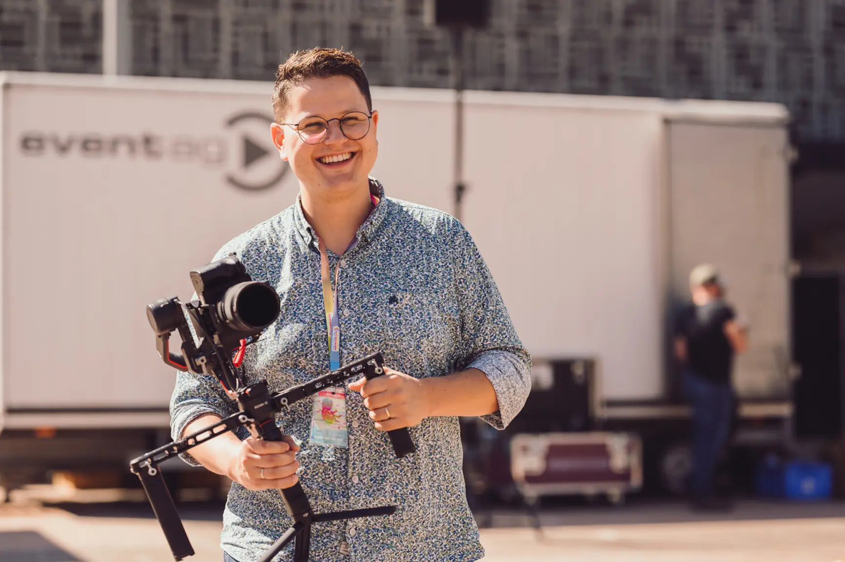 Cornelius während er am Filmen ist. Er hält einen Gimbal, auf dem eine Kamera montiert ist und lacht.